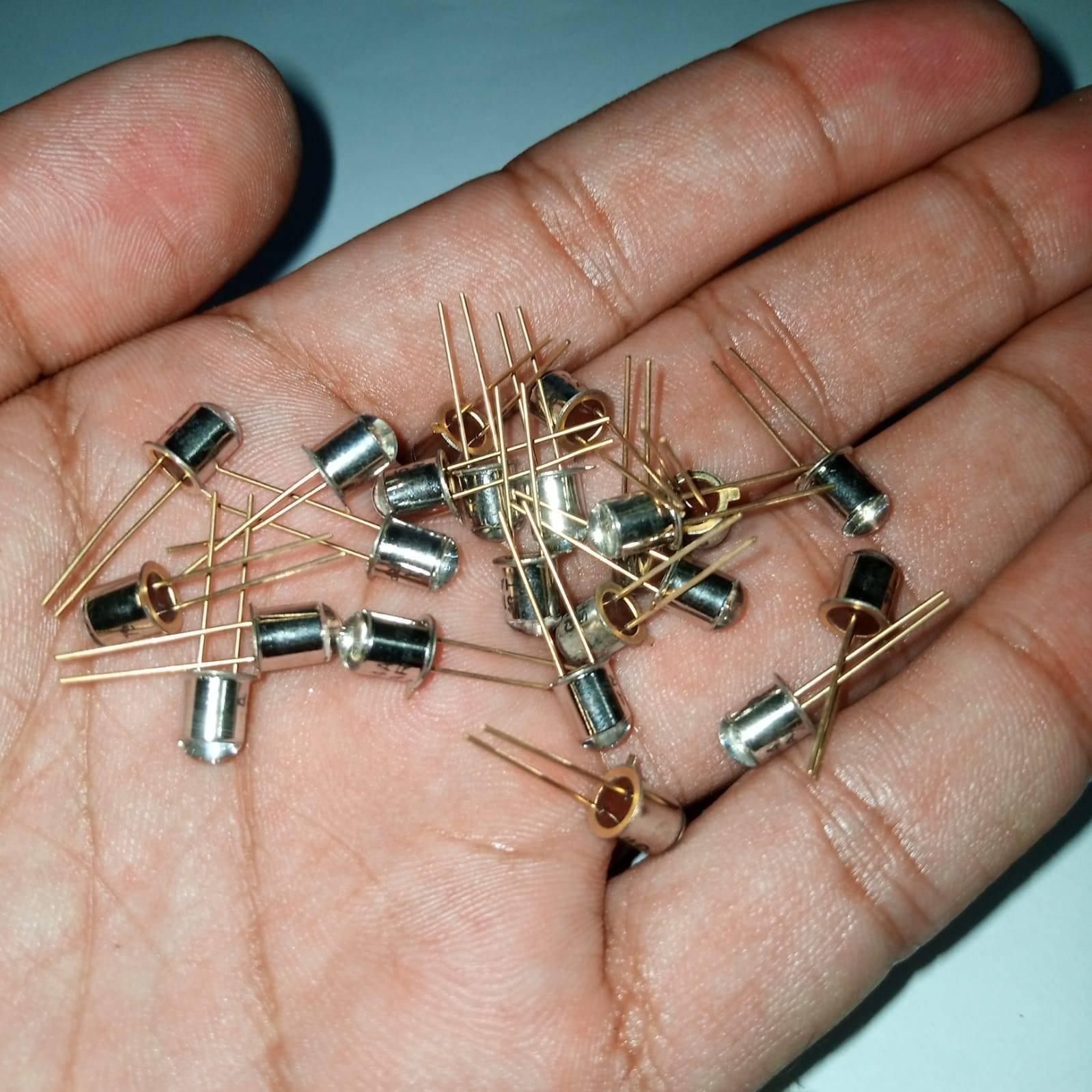 Sharp Infrared Emitting LED Diode GL514A - shown as a pile of small, silver-coloured metal-cased diodes with two gold-coloured pins held in a human hand.