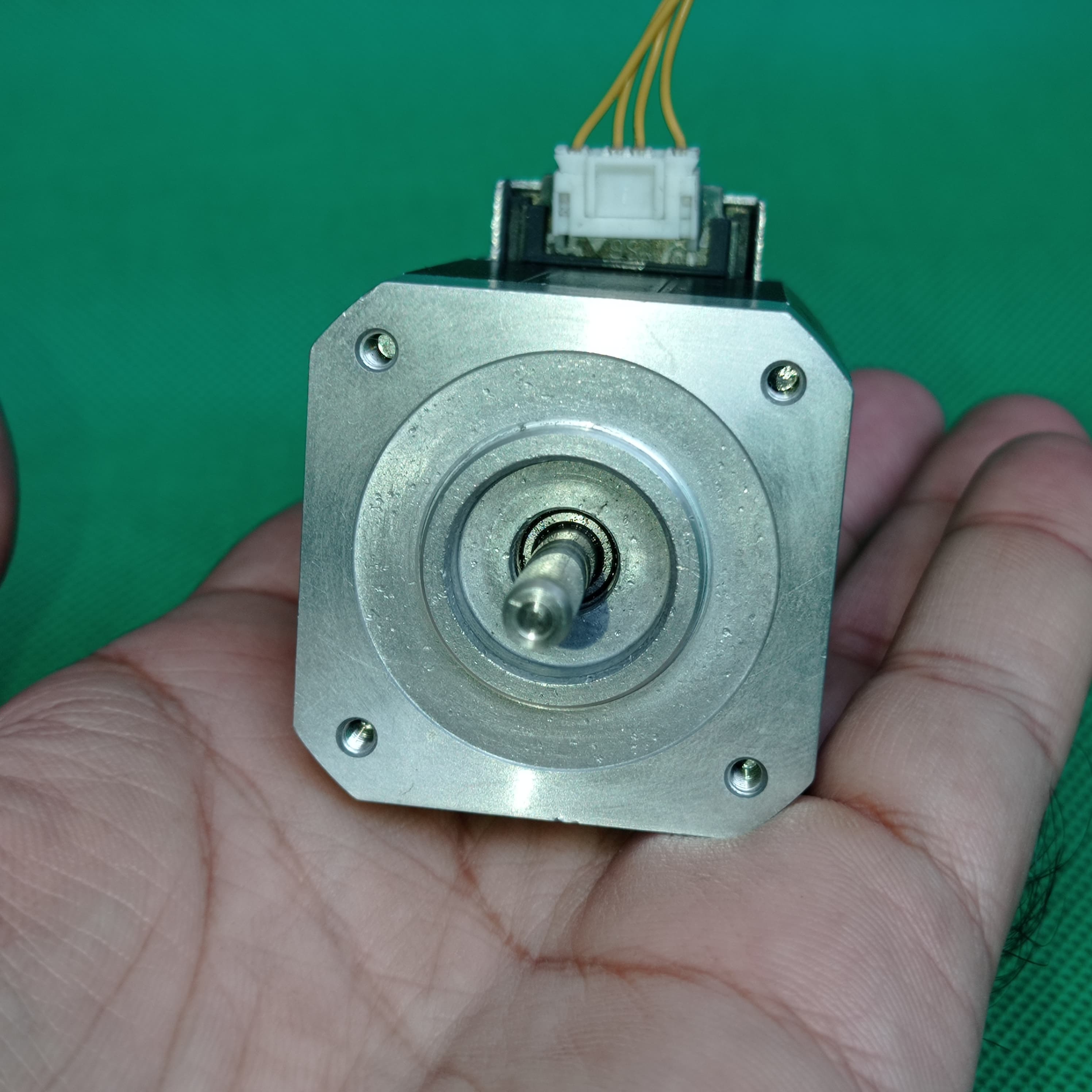 Shinano Kenshi STP-42D4042 2A 1.8 Degree Per Step 0.53nm Stepper Motor - a silver square-bodied motor with a central shaft and a white electrical connector with yellow wires.