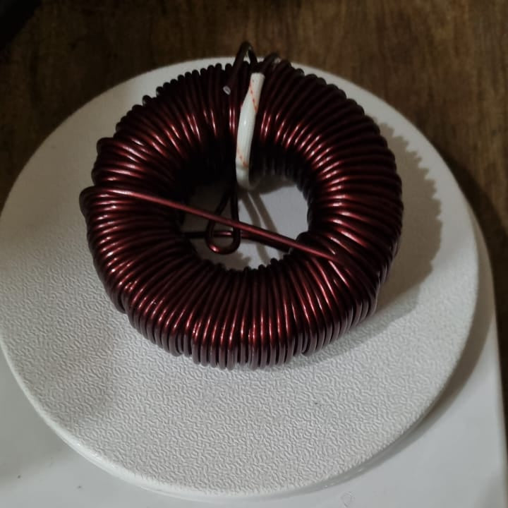 Silver 2.2MH Inductor Coil For Local Solar Inverter - a close-up of a circular copper-colored wire coil wound around a ring-shaped core.