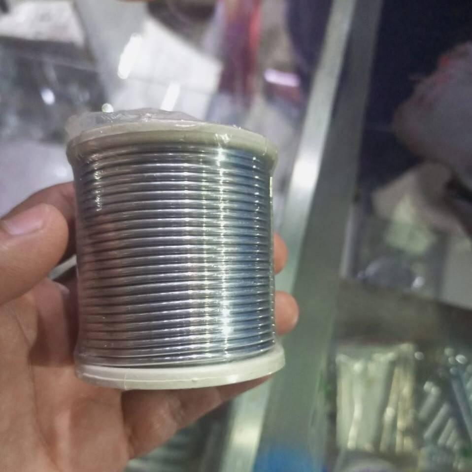 Silver Solder Wire ( Not For Regular USE) - shown as a close-up of a hand holding a spool of thin, metallic silver-colored wire wrapped around a white plastic cylindrical core.