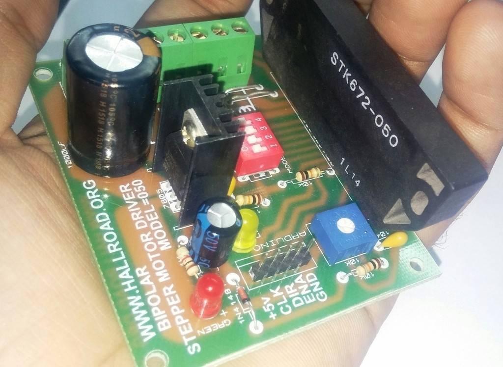 Sine Wave STK672-050 3amp Unipolar 6 Wires Stepper Motor Driver - a green circuit board held in a hand featuring a large black IC, a red DIP switch, a blue potentiometer, and LEDs.