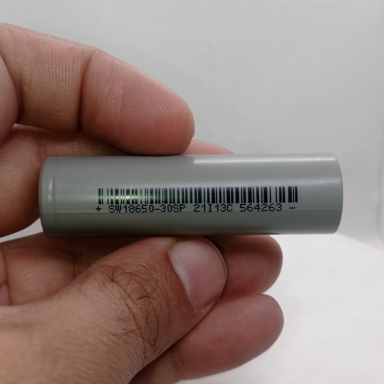 Sinowatt SW18650-30SP 3000mAh High Discharge Rate Cell - lithium cell held between fingers, with the barcode and SW18650-30SP marking printed along the grey cell body.