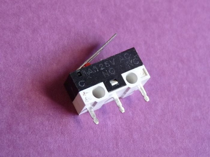 Small Microswitch / Limit Switch - a black and white rectangular limit switch with a metal lever and three metal contact pins, resting on a purple surface.