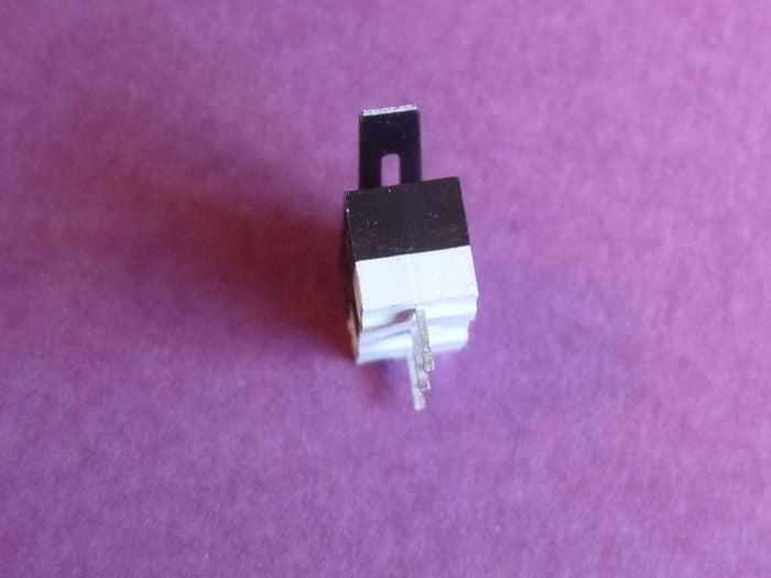 Small Microswitch / Limit Switch - a close-up side view of a black and white rectangular switch body with a metal actuator lever and three metal terminal pins.