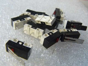 Small Microswitch / Limit Switch - shown as a pile of black and white rectangular switches with red buttons and metal levers on a white textured surface.