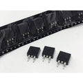 SMD IRF9540 MOSFET - P-Channel Power MOSFET TO263-3 MOSFET -100V -23A - three black TO-263 packaged components placed in front of a black plastic carrier tape strip containing identical units.