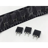 SMD IRF9540 MOSFET - P-Channel Power MOSFET TO263-3 MOSFET -100V -23A - three black TO-263 packaged components placed in front of a black plastic carrier tape strip containing identical units.
