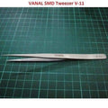 SMD Tweezer Vanal v 11 For Positioning Components - a silver-colored, pointed metal tweezer lying horizontally on a green cutting mat.