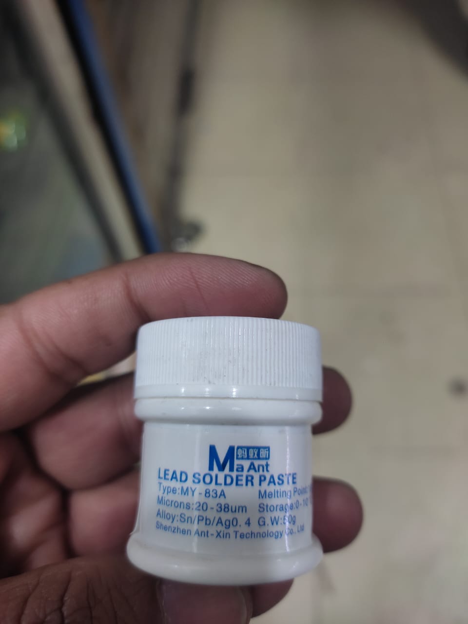 Solder Paste (183°C) MaAnt Model MY-83A Weight 50G - a small white cylindrical plastic container held in a hand, showing the product label with brand and technical specifications.
