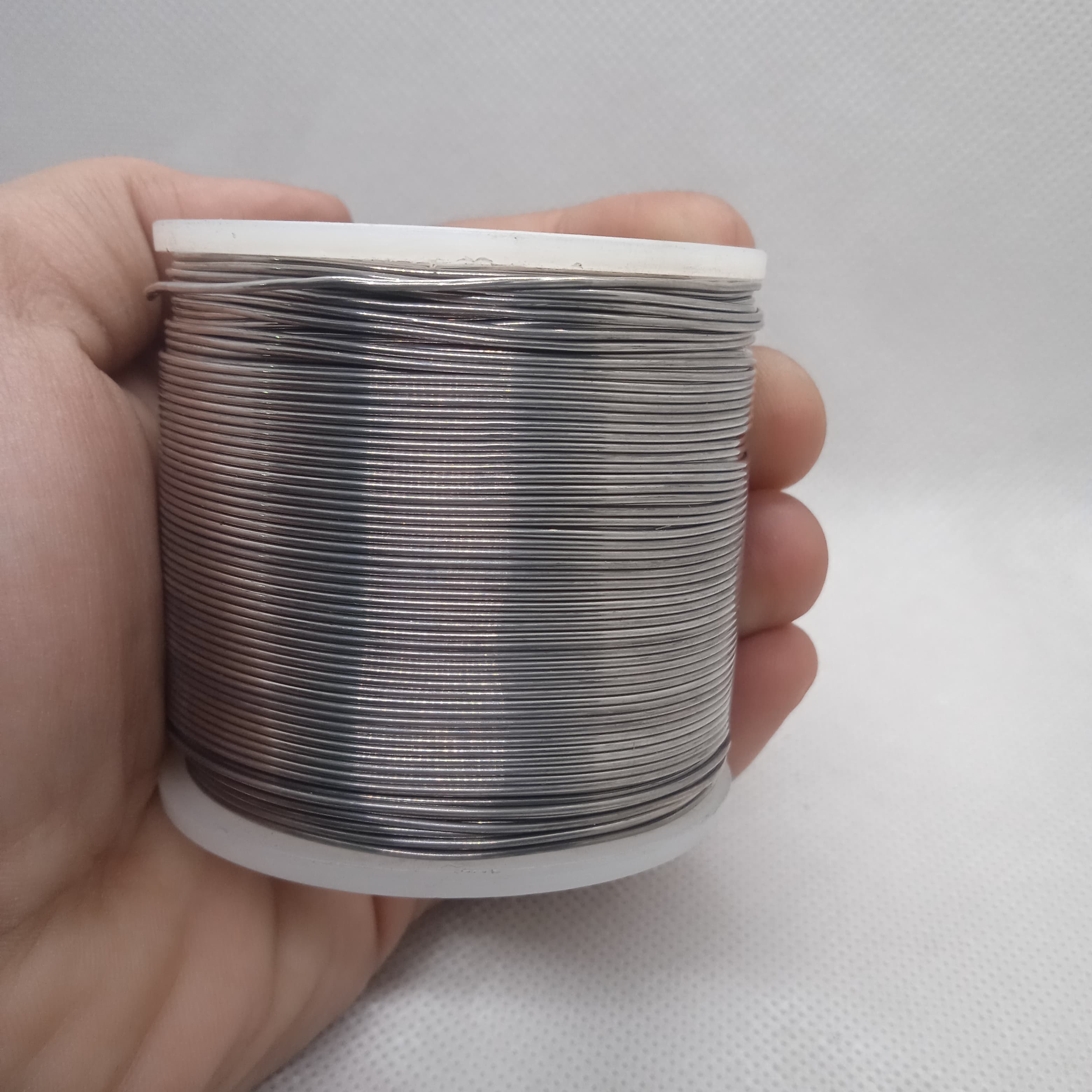 Solder Wire - High Quality 63-37 Professional Solder 400G | digilog.pk - shown as a large spool of silver-colored metal wire held in a person's hand.