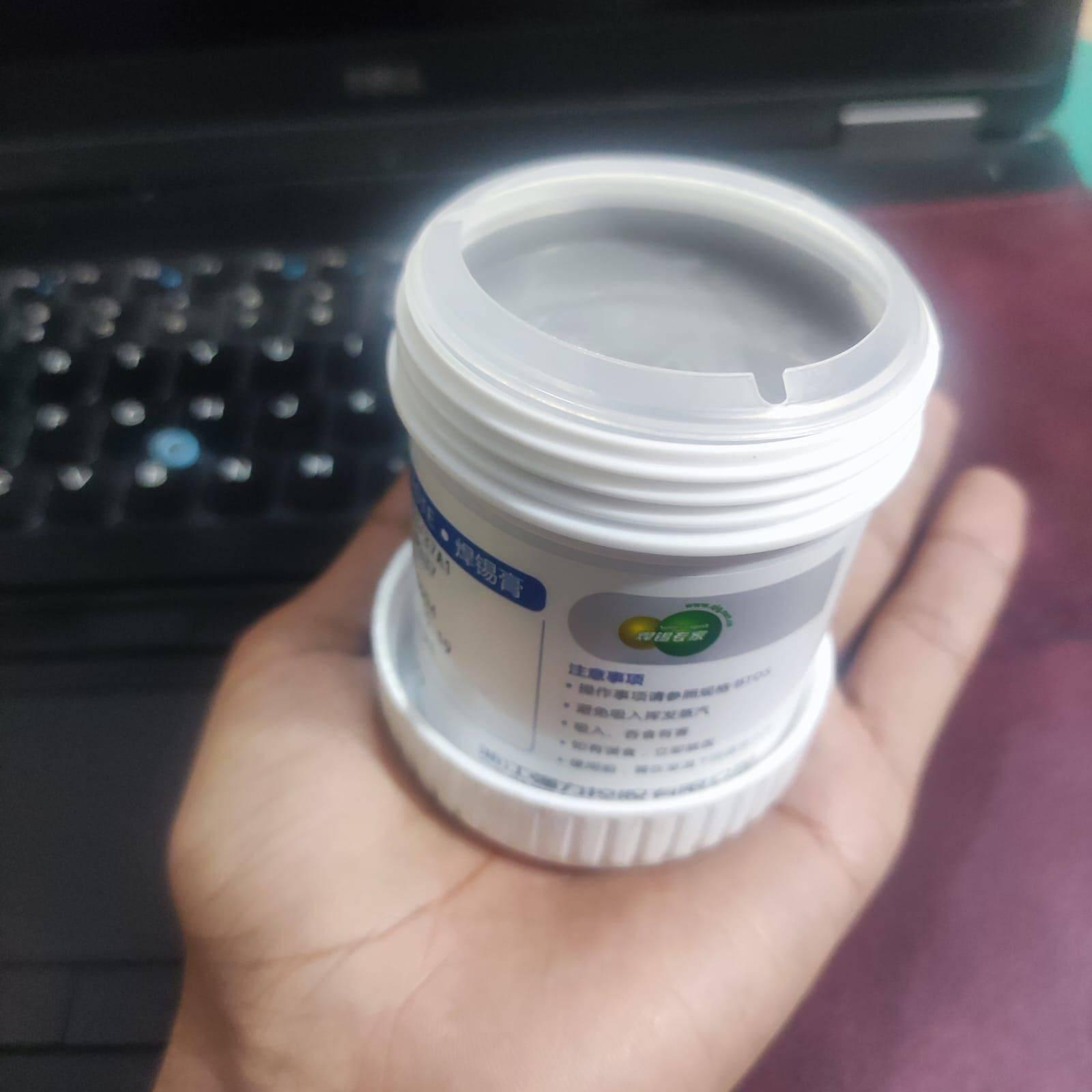 Soldering Flux Paste 500gram Soldering Tin Qlg Factory Solder Welding Rosin Flux SN63PB37 - a white plastic jar with a screw-top lid held in a person's hand, featuring a label with Chinese text and a logo.