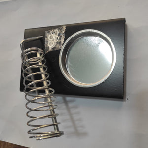 Soldering Iron Stand Holder - a black metal base, a coiled wire spring holder, a circular tray, and a small plastic bag of screws.