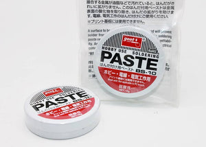 Soldering Paste High Quality - shown as two small, round white tins with red and black labels, one inside a clear plastic bag and one sitting in front.