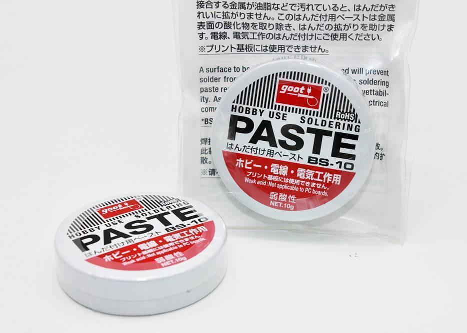 Soldering Paste High Quality - shown as two small, round white tins with red and black labels, one inside a clear plastic bag and one sitting in front.