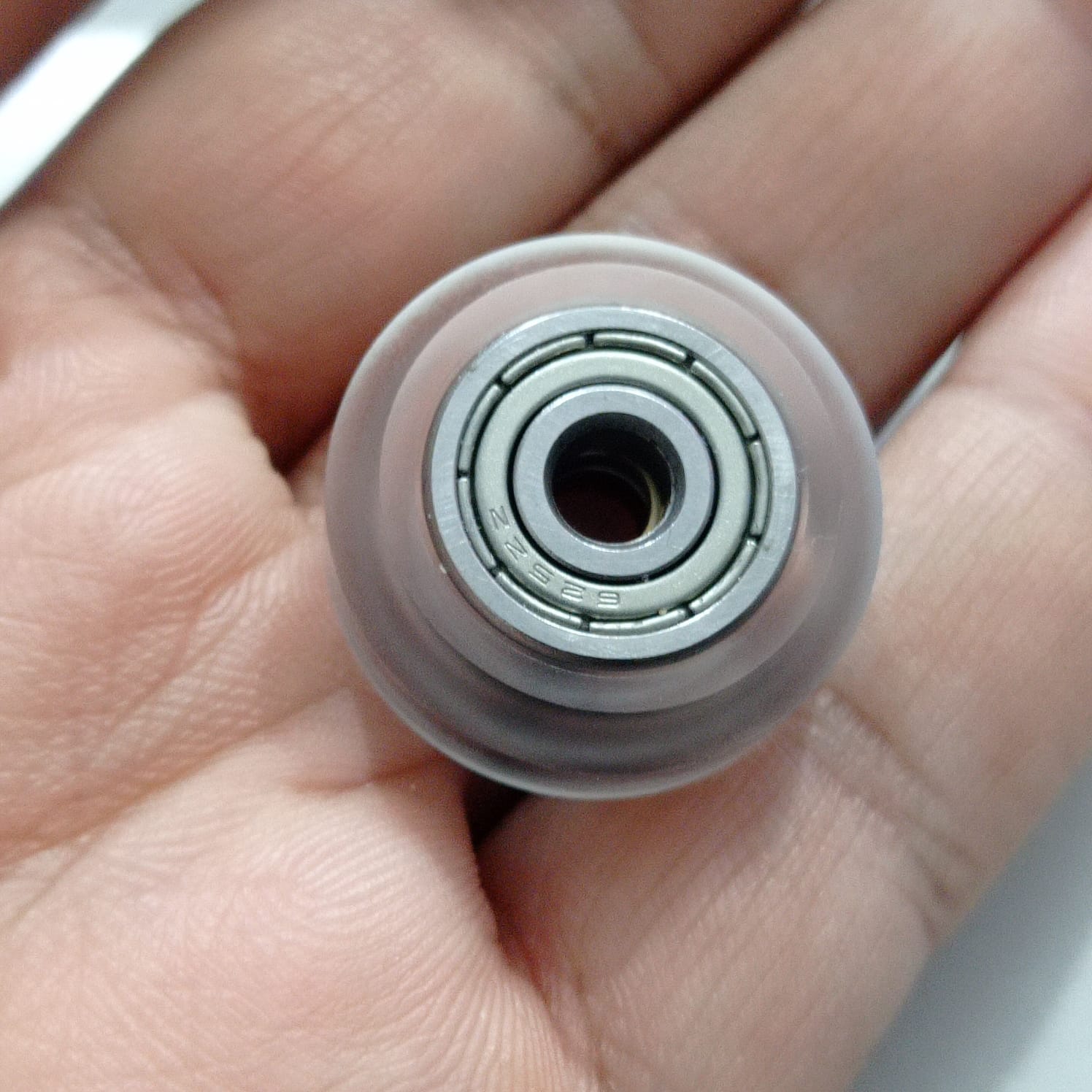 Solid V Wheel For 4040 Aluminum Profile Transparent - close-up of a clear plastic wheel with a metal 625ZZ bearing centered inside, held in a hand.