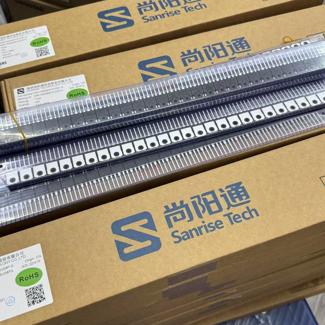 SRE100N65 IGBT - High-Performance Transistor for Power Electronics - shown in a clear plastic storage tube resting on top of brown cardboard boxes branded with the Sanrise Tech logo.