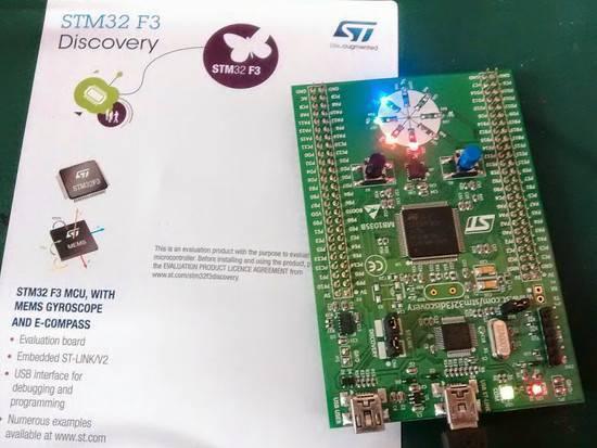 Stm Discovery Kit STM32F3 STM32F303VC With Programming Cable - shown with its green evaluation board featuring LEDs, buttons, and ports next to its printed product information sheet.