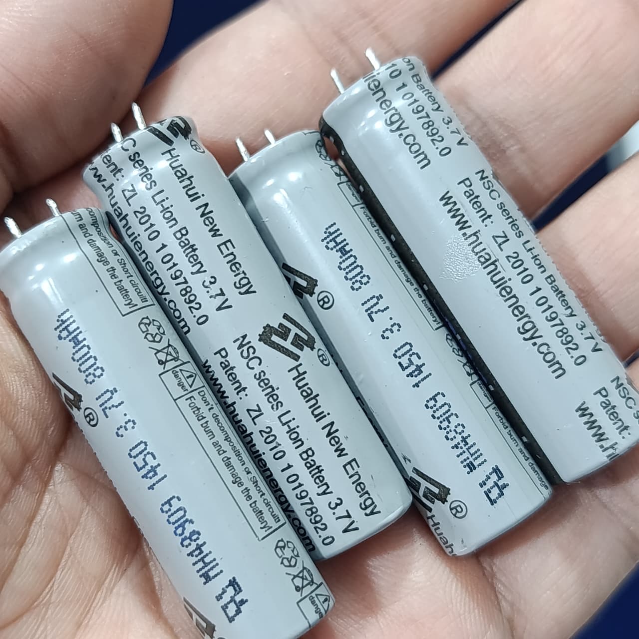 Stock Lot 3.7V 800mAh Lithium Battery 14mm x 50mm 2-Pin Rechargeable (Li-ion Cylindrical Cell) - a close-up of four grey cylindrical Li-ion cells held in a hand.