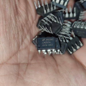 Stock Lot LM2574 Adj Voltage Buck Regulator IC - a close-up shot of a black, multi-pin integrated circuit held in a hand with several other identical units.