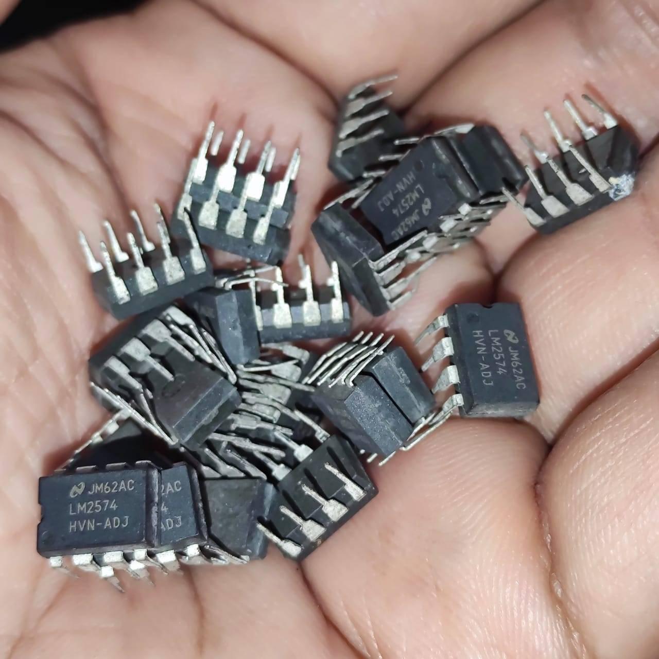 Stock Lot LM2574 Adj Voltage Buck Regulator IC - a pile of black, rectangular, 8-pin integrated circuit chips held in a human hand.