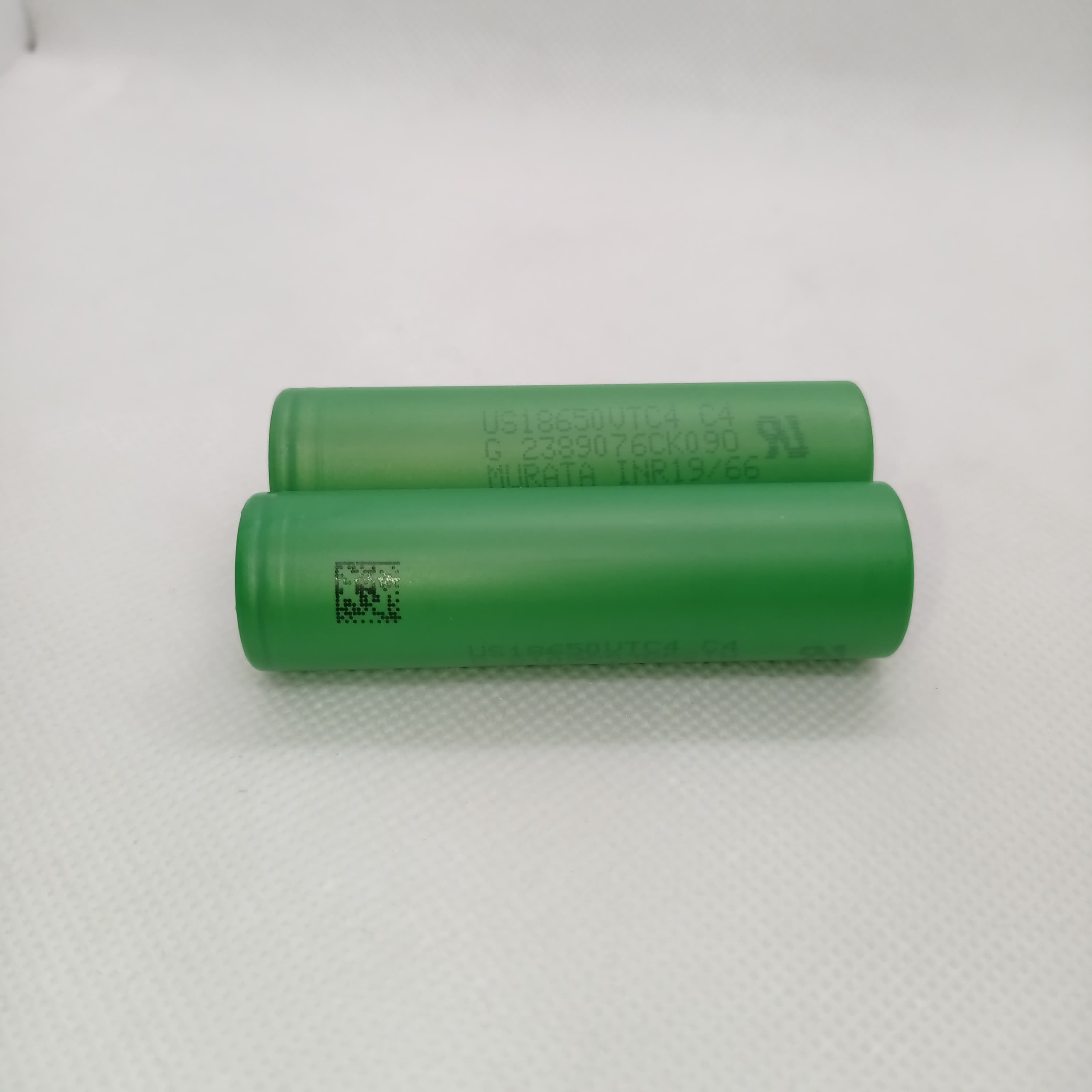 Stock Lot US18650UTC4 3.7V 2000mA 18650 Li-ion Rechargeable Battery – High-Capacity Power Cell for Flashlights, Laptops, and Power Tool - two green cylindrical cells lying horizontally with printed text and a QR code visible.