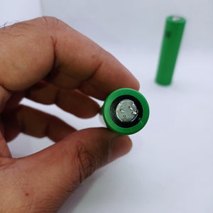 Stock Lot US18650UTC4 3.7V 2000mA 18650 Li-ion Rechargeable Battery – High-Capacity Power Cell for Flashlights, Laptops, and Power Tool - a close-up of the green cylindrical cell's positive terminal held in a hand with another in the back.