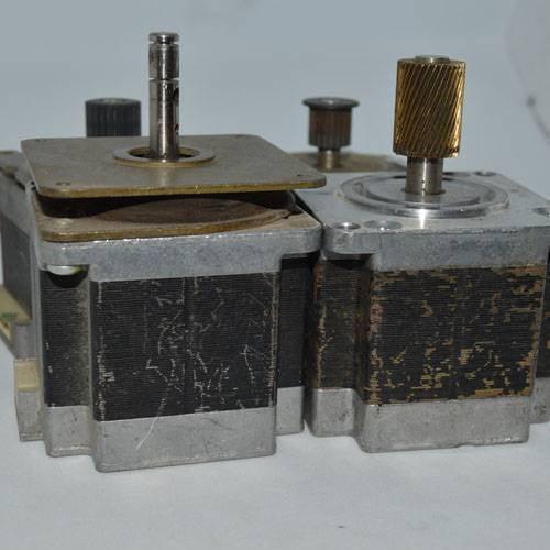 Stock Lot Used Bipolar NEMA 23 Stepper Motor Lot - two silver and black metal stepper motors with shafts and attached gears.
