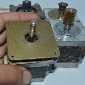 Stock Lot Used Bipolar NEMA 23 Stepper Motor Lot - three silver-toned square stepper motors, one held in a hand with a smooth shaft and two with gears.
