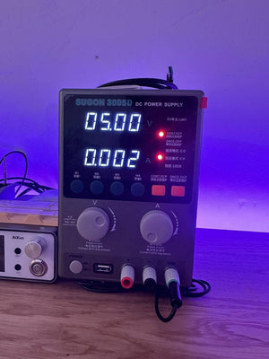 Sugon 3005D Regulated Power Supply - a grey unit with a digital display reading 05.00 V and 0.002 A, control knobs, buttons, and output terminals.