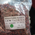 T2A250V PCB Mount 2A Miniature Fuse - shown as a bulk pack of 1000 brown, square-shaped radial fuses inside a clear plastic bag with a product label.