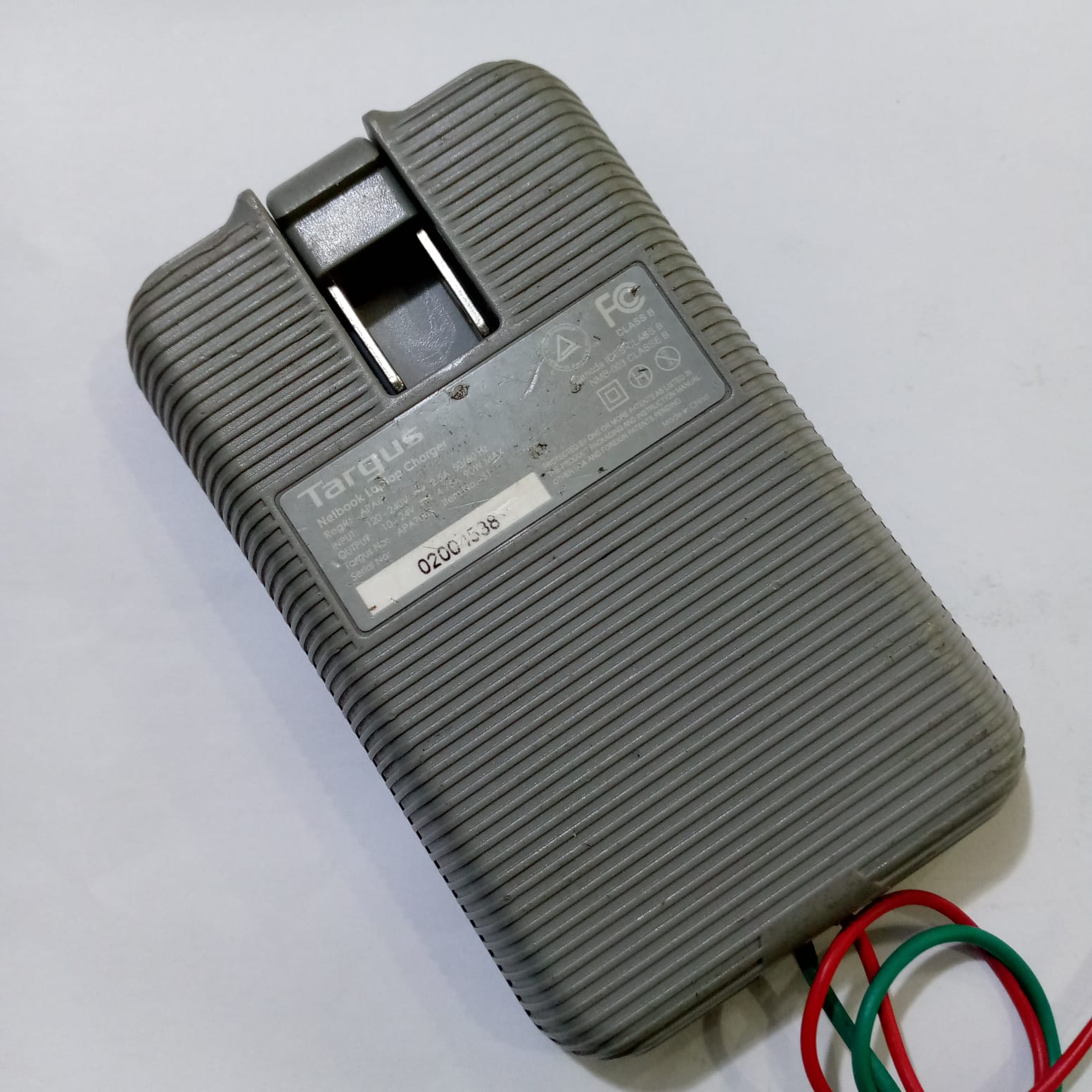 Targus Apa Power Supply 24V 4.75A - shown from the back, featuring a grey, ribbed rectangular casing with a serial number label and attached power cables.