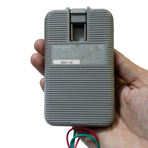 Targus Apa Power Supply 24V 4.75A - shown as a grey, rectangular, ribbed-textured charger held in a hand with exposed green and red wires at the bottom.