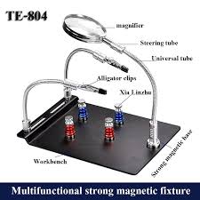 TE-804 Soldering Third Hand Magnetic Universal PCB Motherboard Fixture With Magnifier - a black magnetic workbench with two flexible arms, alligator clips, and a magnifying glass on a universal tube.