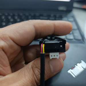 TEUCER M.2 SSD Heatsink NVME 2280 - Aluminum Cooling Radiator for Desktop PC & PS5 - a close-up of the black cooling unit held in a hand, showing its three-pin white connector and red and yellow wires.