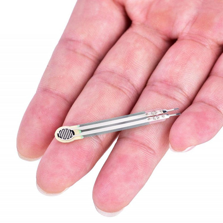 Thin Film Pressure Sensor FSR High Accuracy Flexible Analog Resistor RP-C7.6-LT - a small, beige, flexible, flat sensor with two long, thin, silver-coloured contact strips held in a hand.
