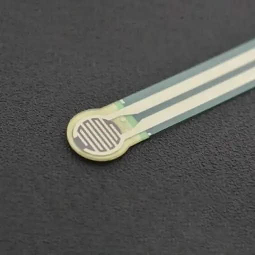 Thin Film Pressure Sensor FSR RP-C7.6-LT-LF2 Flexible High Sensitivity 30G to 8KG - a close-up of the flexible, circular-headed sensor with a white interdigitated pattern on a dark surface.
