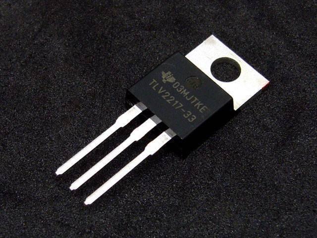 TLV2217-33 TLV2217 3.3 Low Dropout Regulators - a black electronic component with three metal pins and a mounting tab with a hole, set against a black background.