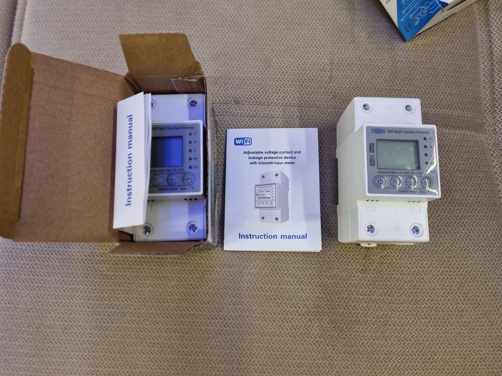 Tomzn 63A WiFi Smart Switch Tuya Energy Meter kWh Metering Circuit Breaker Timer With Voltage Current And Leakage Protection - two white DIN-rail units, one inside an open cardboard box, with an instruction manual placed between them.