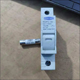 TOMZN TOPV-32X DC 1100V PV Fuses for Solar System Protection - holder in white plastic with a cylindrical 10x38 solar fuse placed horizontally beside it on a wooden surface.