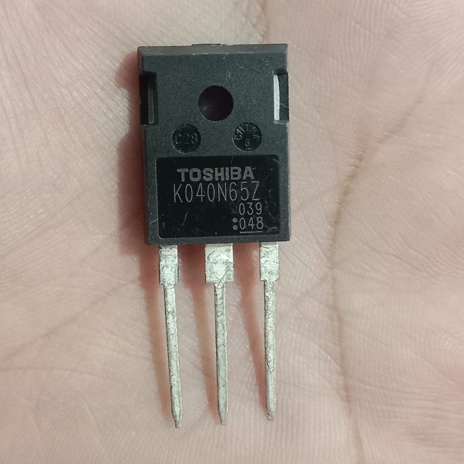 Toshiba K040N65Z N-Channel Power MOSFET - a black, three-pin electronic component held in a hand, showing the printed model number on its front surface.