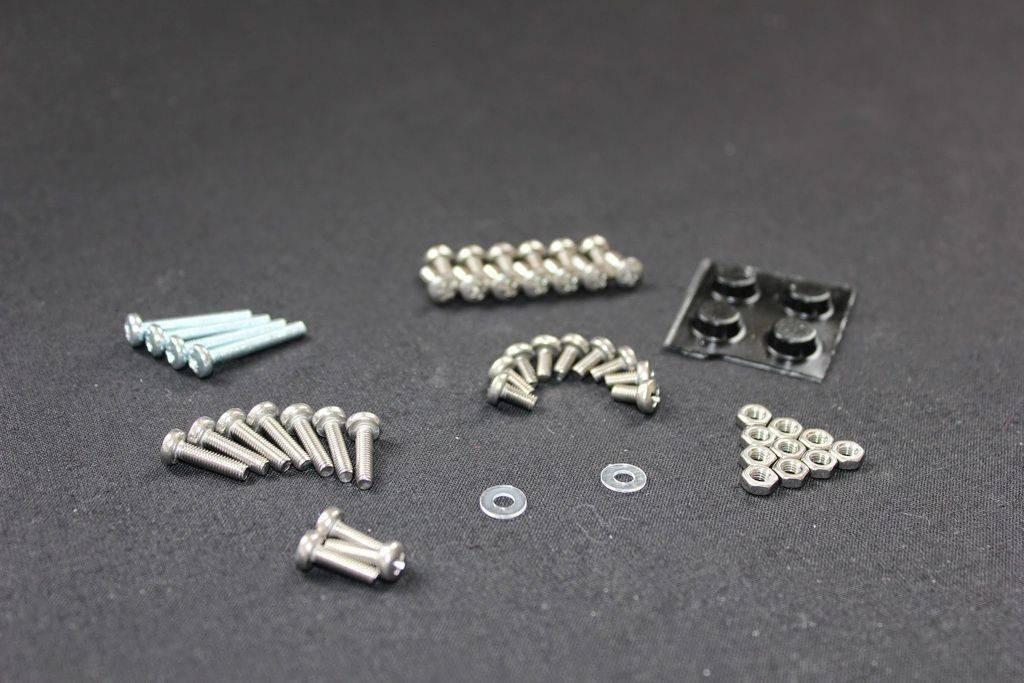 Unassembled 4dof Robotic Arm - an assortment of metal screws, nuts, washers, and four black rubber feet on a black surface.
