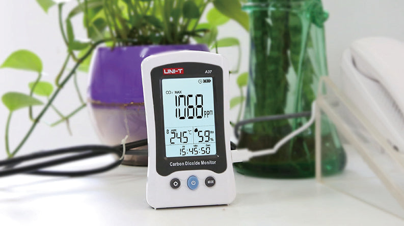 UNI-T A37 CO2 Meter – 400–5000 PPM Carbon Dioxide, Temperature, NDIR Air Quality Monitor, Rechargeable - a white handheld monitor showing 1068 ppm, 24.5°C, 59% RH, and 15:45:50 on its display, connected to a charging cable.