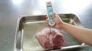UNI-T A63 2-in-1 Food Thermometer – Infrared + Fold-Out Probe, -40 to 300℃, Laser Targeting, Kitchen / BBQ Cooking Thermometer - with a white body and silver probe inserted into raw meat, showing 26.5 on its digital display.