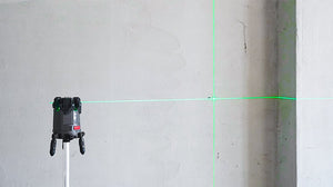 UNI-T LM555LD 4D Green Laser Level – 4V1H + Plumb Point, ±2 mm/10 m, Self-Leveling, 130° Lines, IP54, Rechargeable - projecting horizontal and vertical green laser lines onto a plain wall with a visible red power button.
