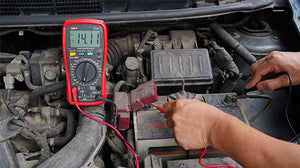 UNI-T UT107+ True RMS Automotive Multimeter – 6000 Count, RPM, Dwell Angle, Pulse Width, Battery Test, Temperature, 1000V AC/DC, VFC, CAT III 600V - a red handheld device with a digital display showing 14.11, being used to test a car battery with probes.