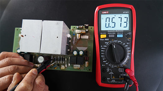 UNI-T UT107+ True RMS Automotive Multimeter – 6000 Count, RPM, Dwell Angle, Pulse Width, Battery Test, Temperature, 1000V AC/DC, VFC, CAT III 600V - with a red casing and black rotary dial, showing a 0.573V reading while testing a circuit board with probes.