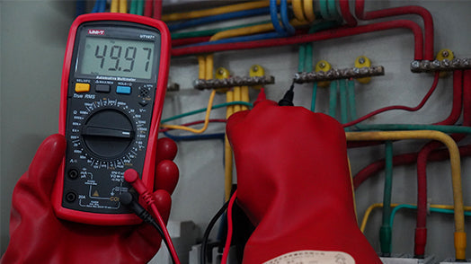 UNI-T UT107+ True RMS Automotive Multimeter – 6000 Count, RPM, Dwell Angle, Pulse Width, Battery Test, Temperature, 1000V AC/DC, VFC, CAT III 600V - held by gloved hands, showing a red casing, rotary dial, ports, and a digital display reading 49.97.