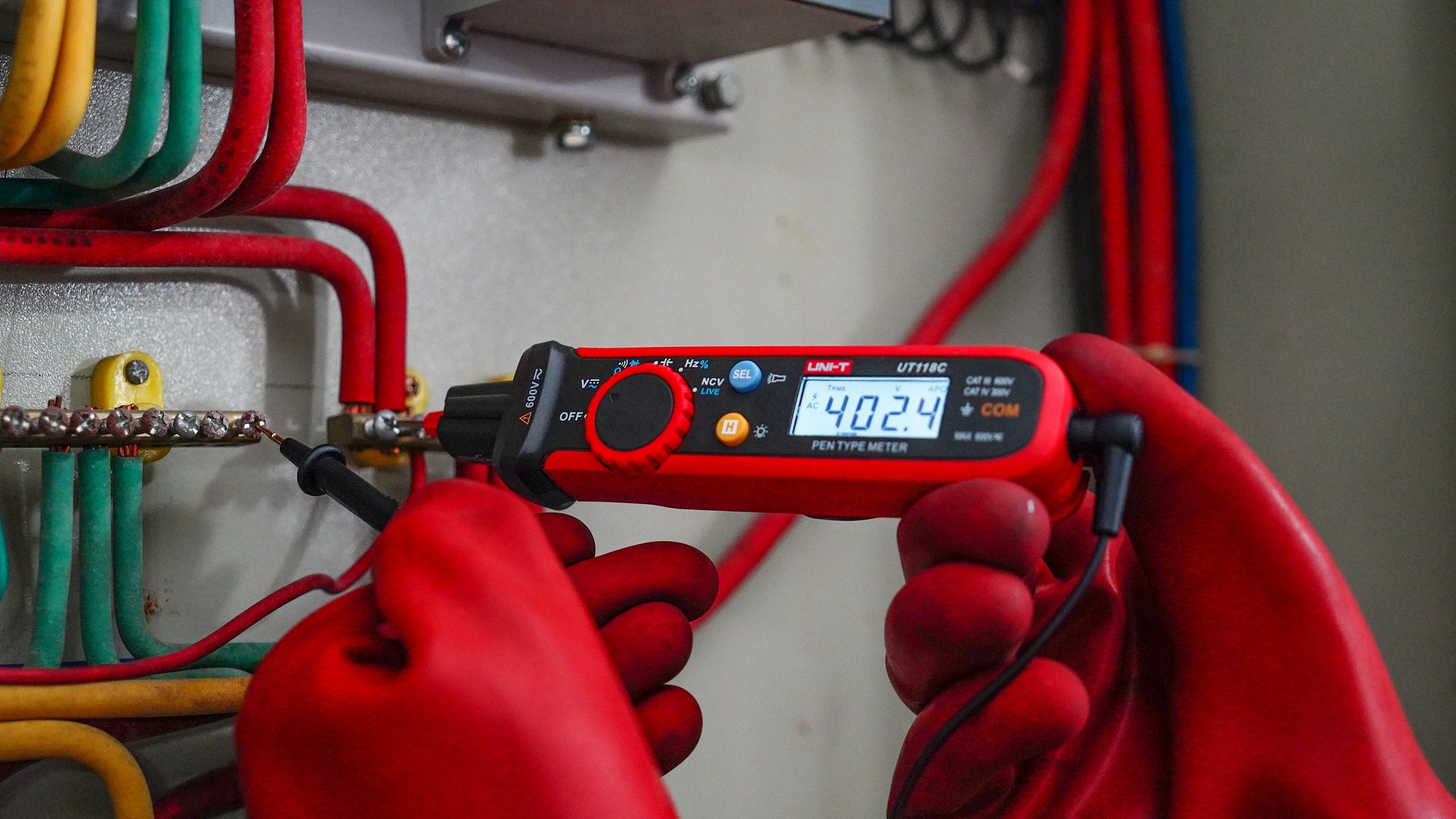 UNI-T UT118C True RMS Pen Type Digital Multimeter – AC/DC 600V, Resistance, Capacitance, NCV, Gold-Plated Tips, CAT III 600V / CAT IV 300V - held by gloved hands, showing a 402.4 reading on its digital display while testing a circuit board.