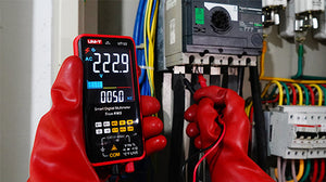 UNI-T UT121B Smart Digital Multimeter – 6000 Count Auto-Identify, True RMS, Dual Display EBTN, AC/DC 600V, 60mF Capacitance, NCV, Live Wire, CAT III 600V - held in red-gloved hands, showing a digital display reading 222.9V and 50Hz while testing electrical components.