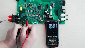 UNI-T UT121B Smart Digital Multimeter – 6000 Count Auto-Identify, True RMS, Dual Display EBTN, AC/DC 600V, 60mF Capacitance, NCV, Live Wire, CAT III 600V - measuring a green circuit board with black and red probes, showing 0.581V on its EBTN display.
